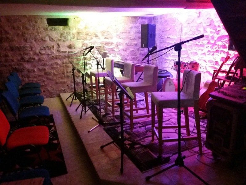 La salle de l’école aménagée en scène, micros et chaises sous une lumière violette.