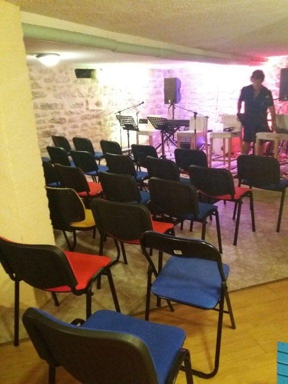 La salle préparée pour un concert : pupitres et éclairage violet.