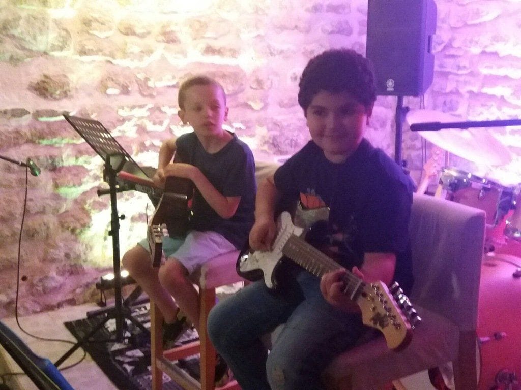 Deux enfants jouent de la guitare électrique côte à côte.