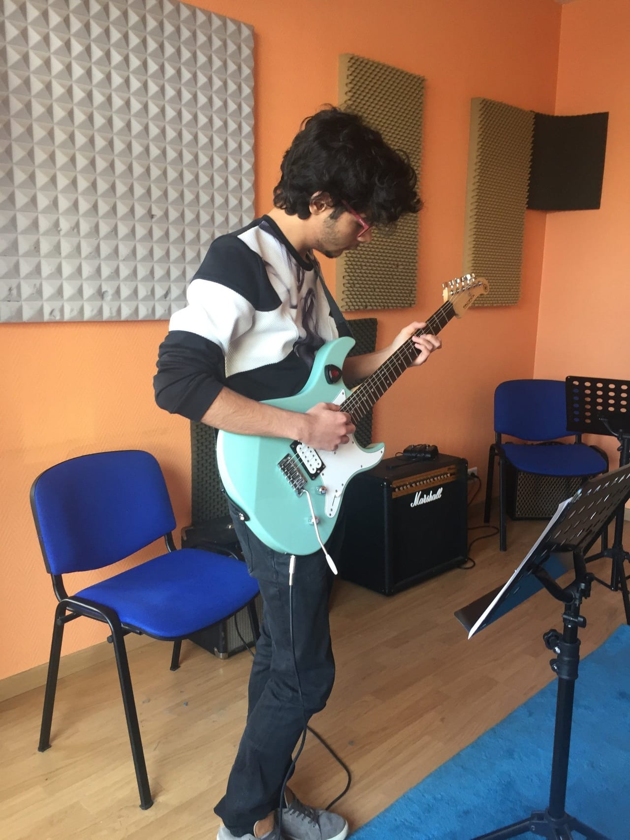 Un élève joue de la guitare électrique devant son ampli.