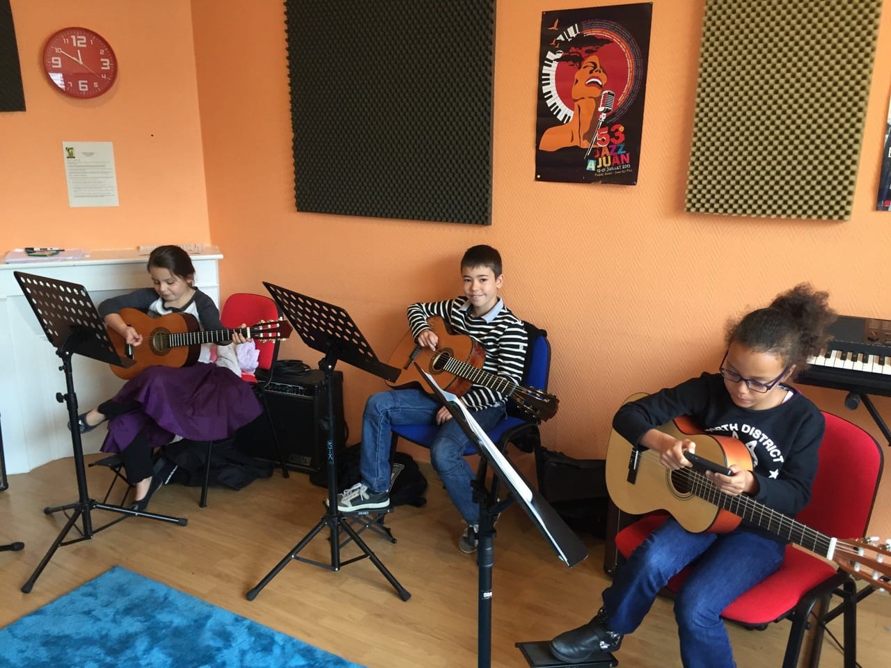 Atelier collectif : des enfants jouent de la guitare, partitions sur les pupitres.
