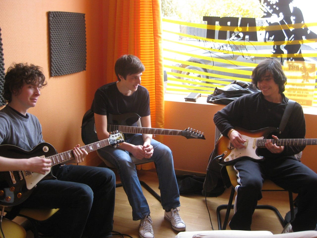 Des adolescents jouent de la guitare électrique en groupe.