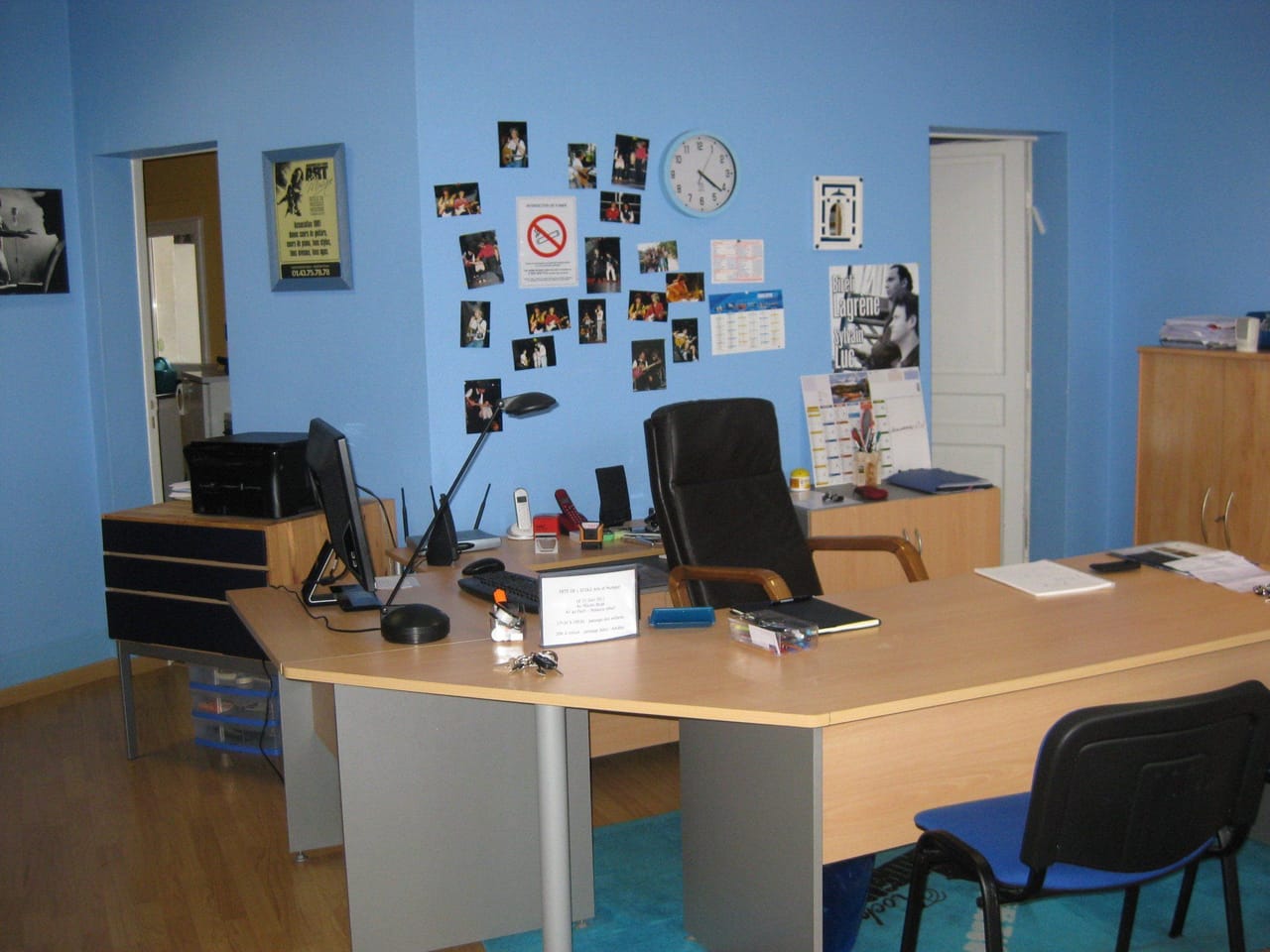 Une salle de l’école : bureau, chaises et mur bleu.