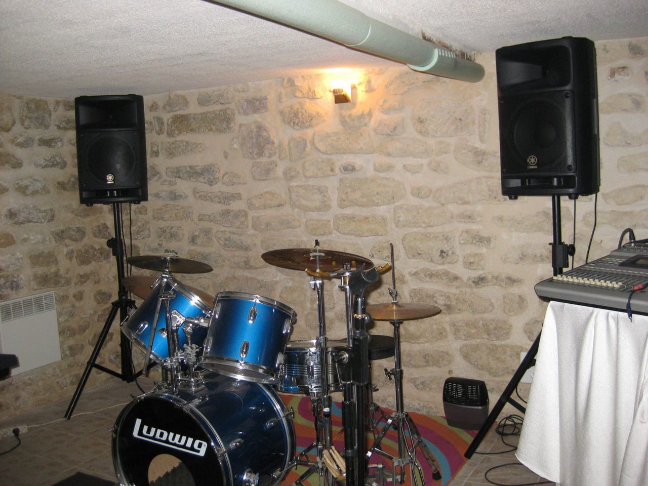 Une batterie et des enceintes dans la salle en pierre.