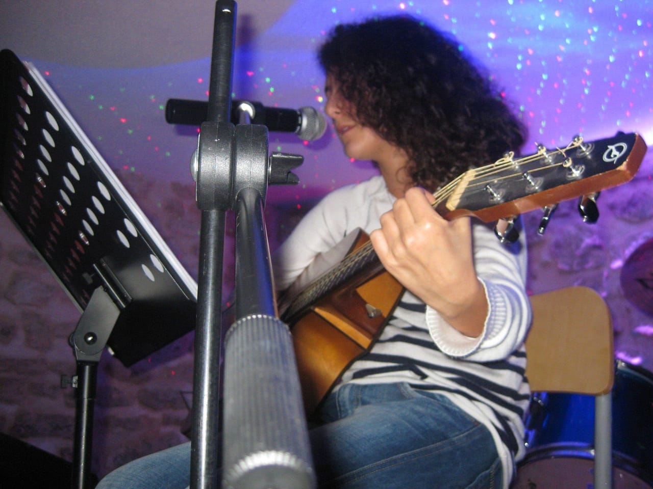 Un guitariste sur scène sous une lumière violette.